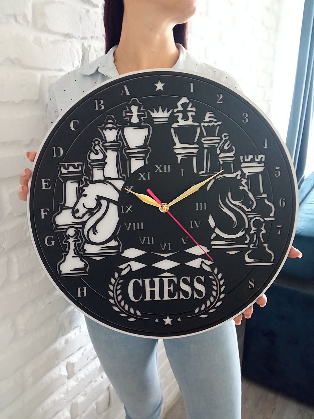 Часы «Шахматы» с фигурами и надписью Chess в руках у кирпичной стены