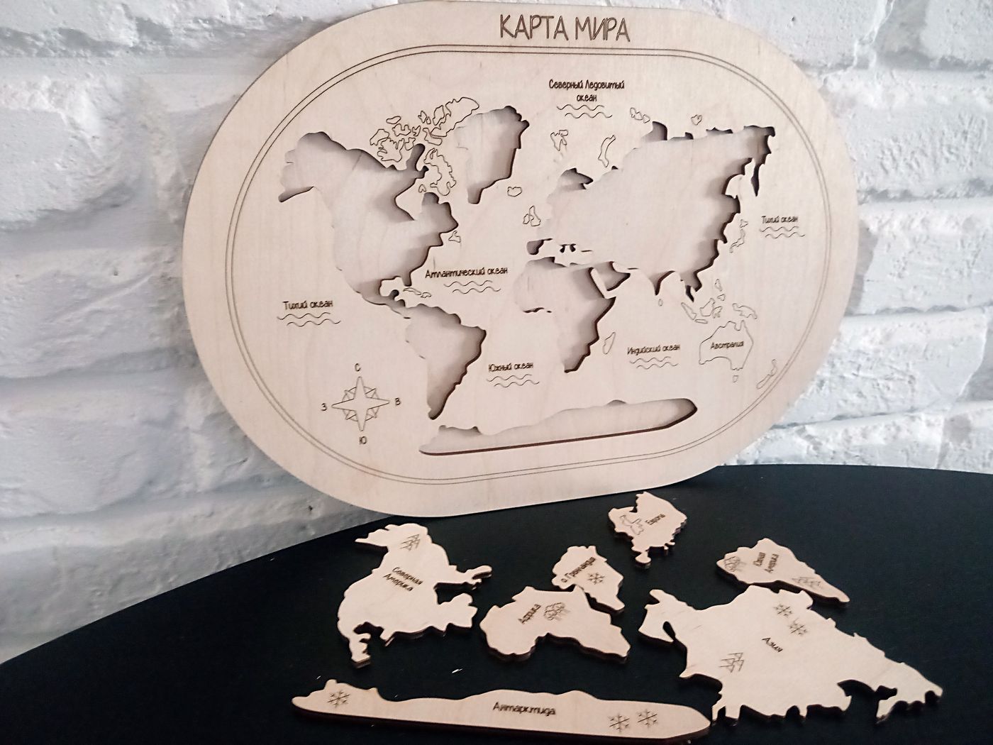 Карта мира из фанеры с вынутыми материками, детали лежат рядом на столе