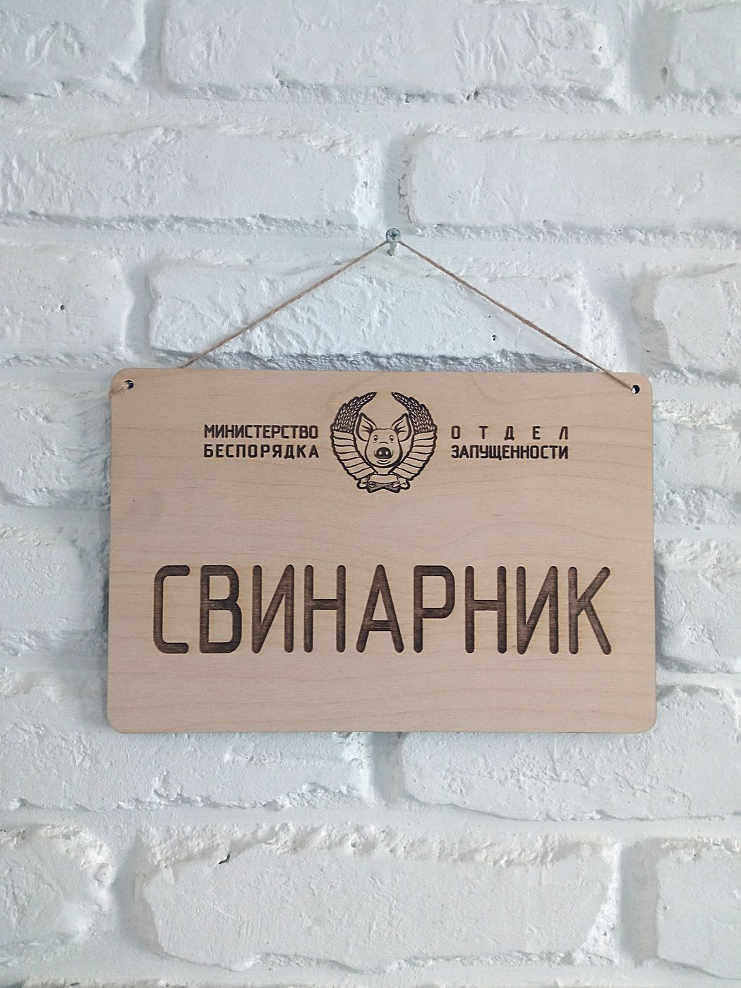 Табличка «Свинарник» крупным планом: гравированный герб и мелкий текст сверху